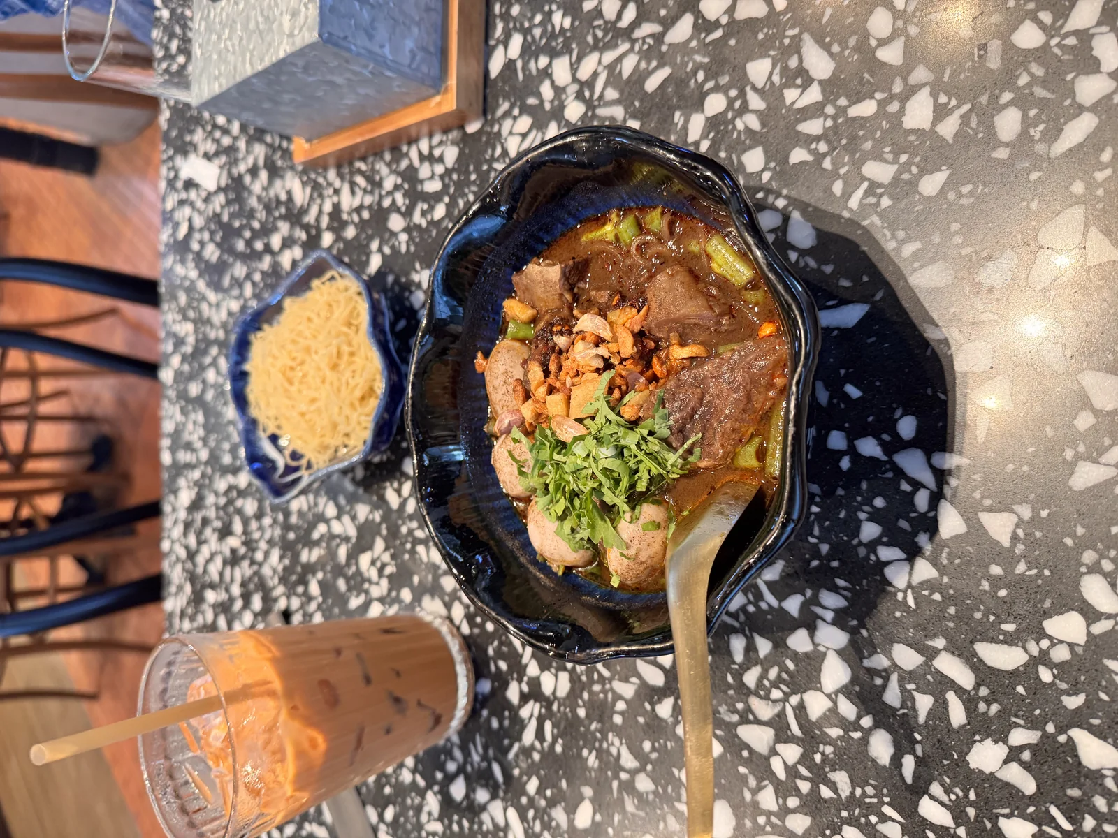 A small bowl of Thai boat noodles with dark pork broth