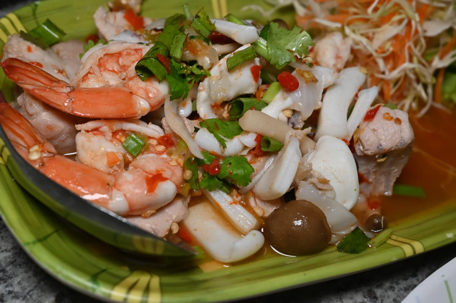 Finished plate of spicy Thai seafood salad with prawns, squid and fresh herbs