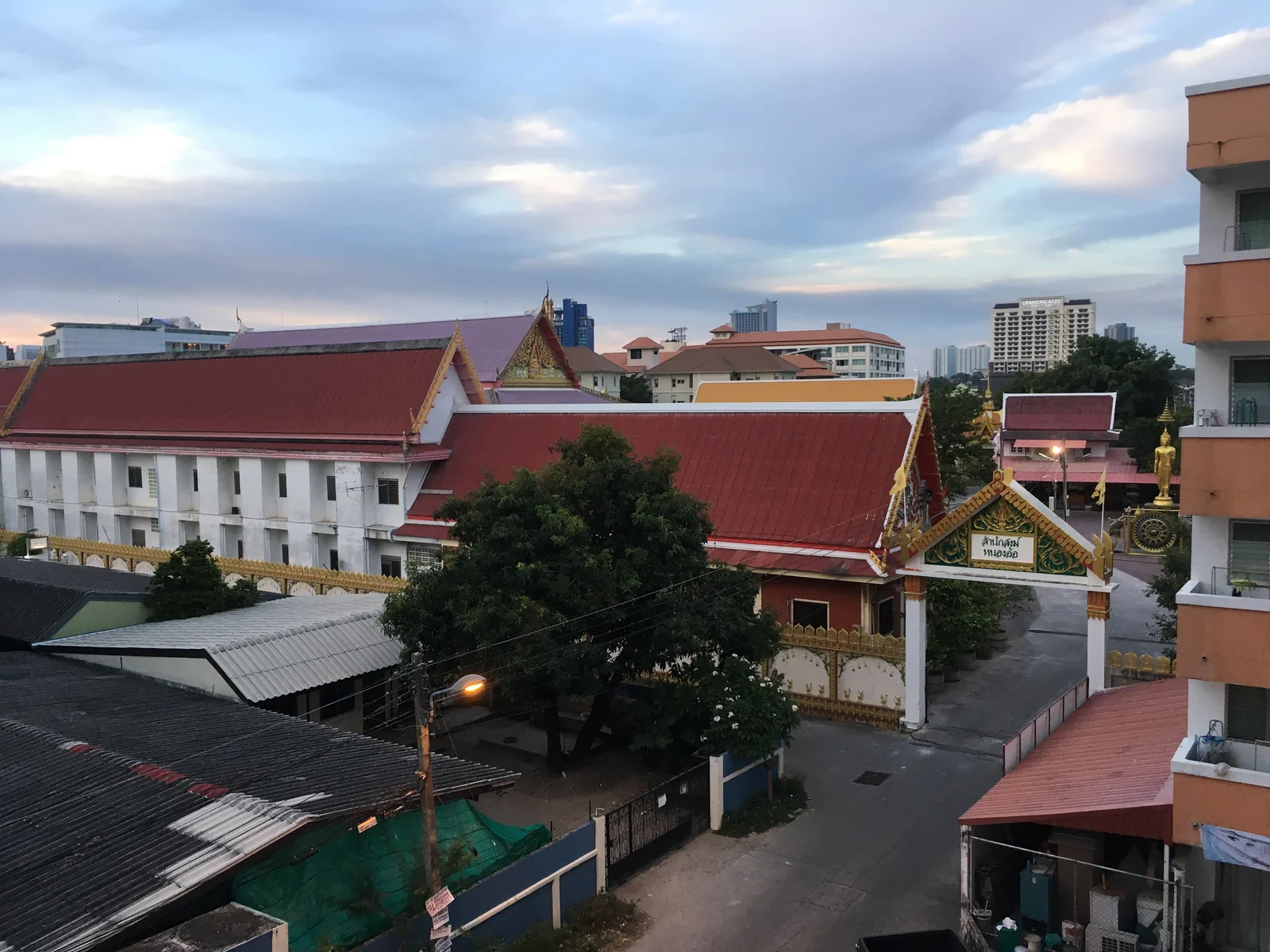 Rooftop view over a Pattaya temple compound at dusk with hotel towers rising behind it