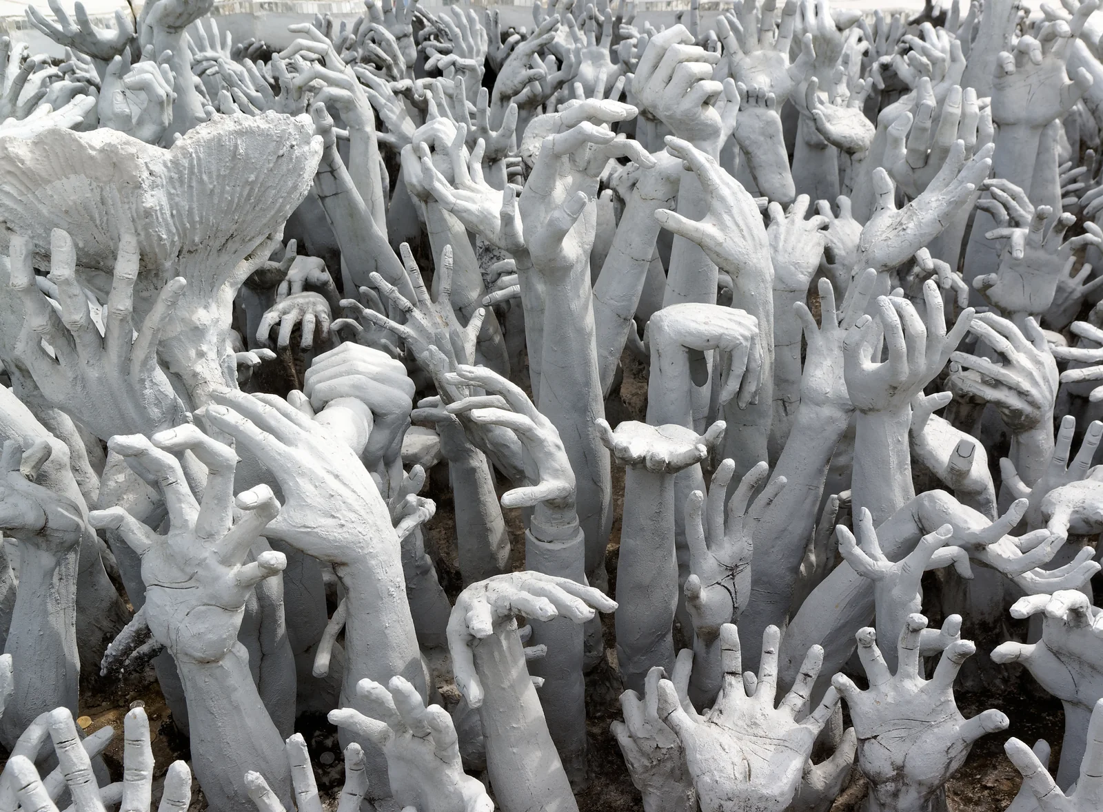 Sculpted reaching hands in the purgatory installation at the White Temple, Chiang Rai