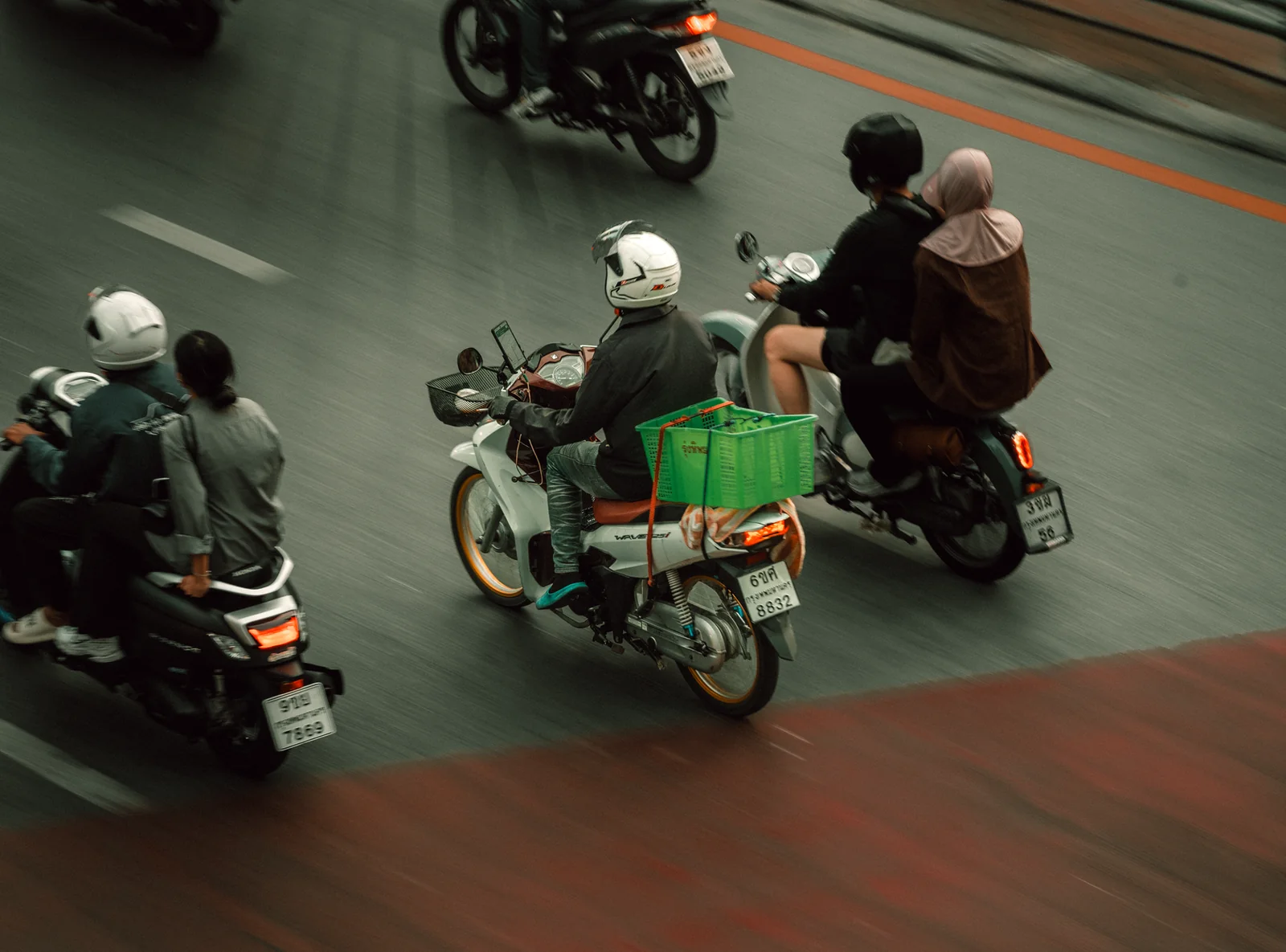 Small automatic motorbike on a rural Thai road with trees on both sides